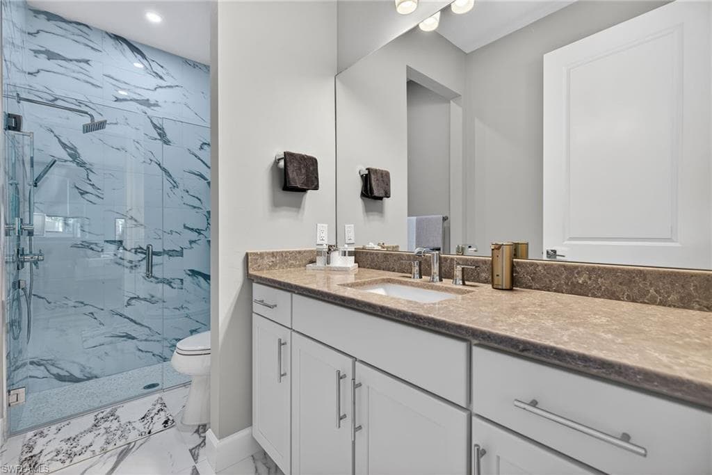 Full bathroom with vanity, a marble finish shower, and light marble finish flooring