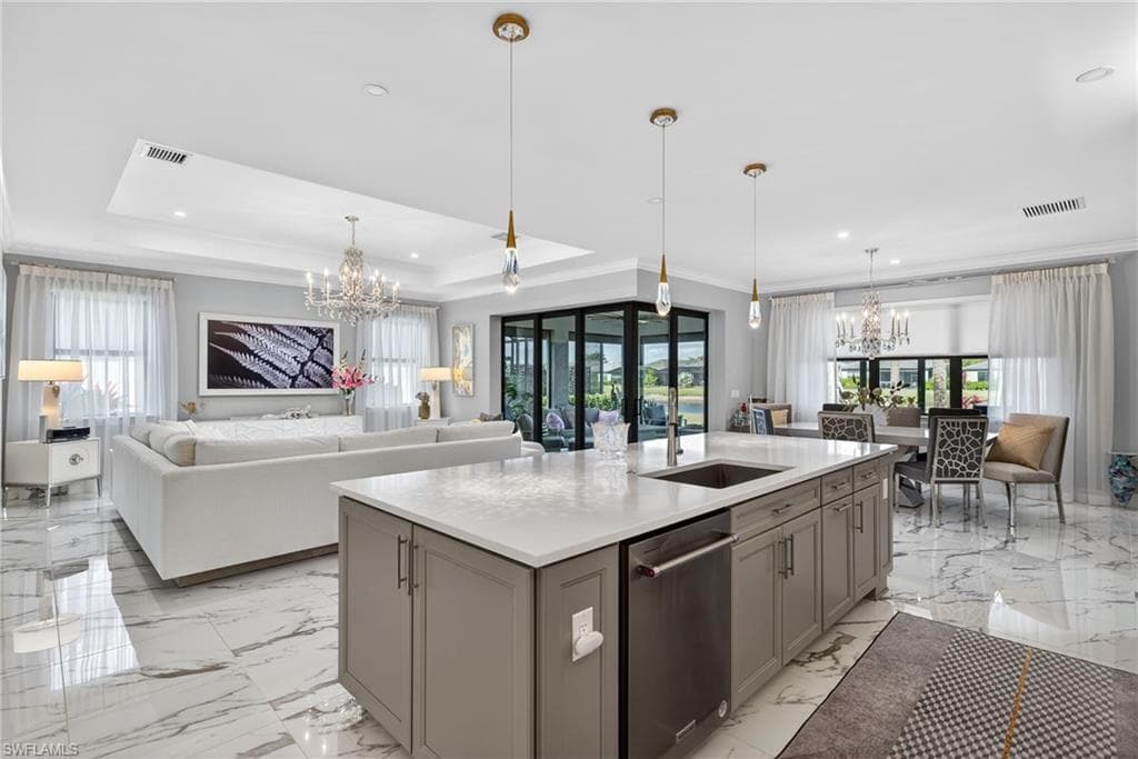 Kitchen featuring a chandelier, open floor plan, ornamental molding, dishwasher, and a kitchen island with sink