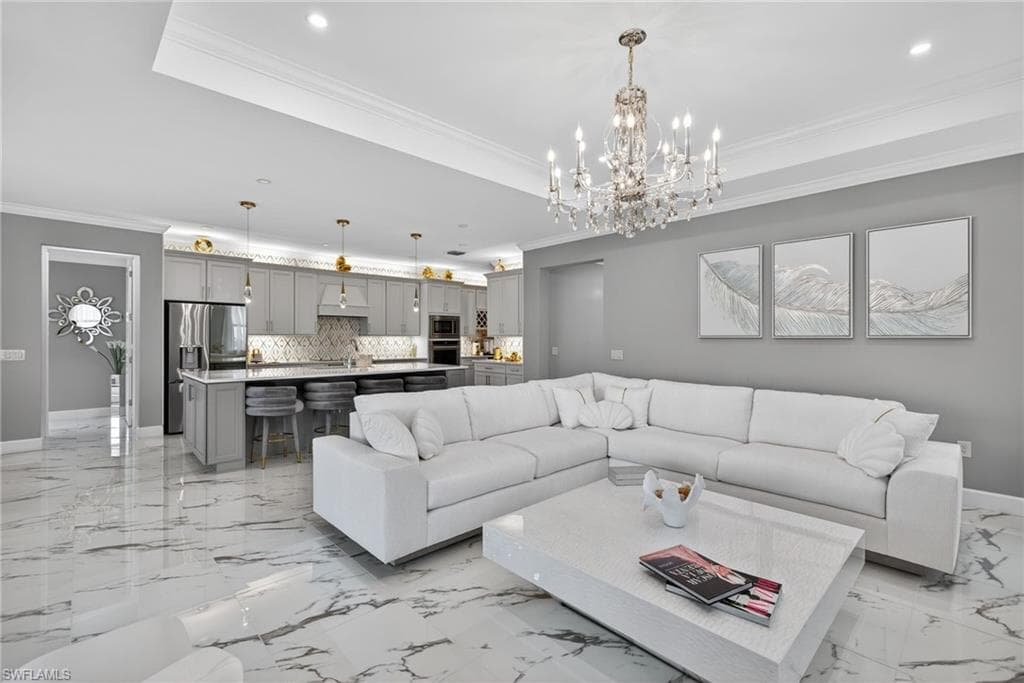 Living area with crown molding, a chandelier, a raised ceiling, and recessed lighting