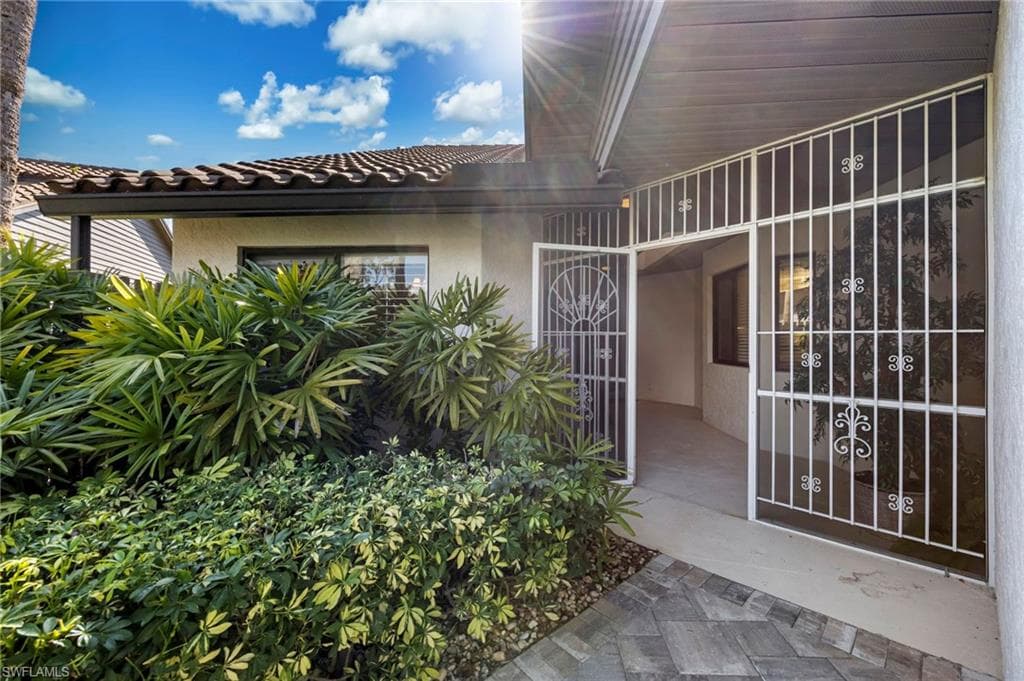 Doorway to property featuring stucco siding and a tiled roof