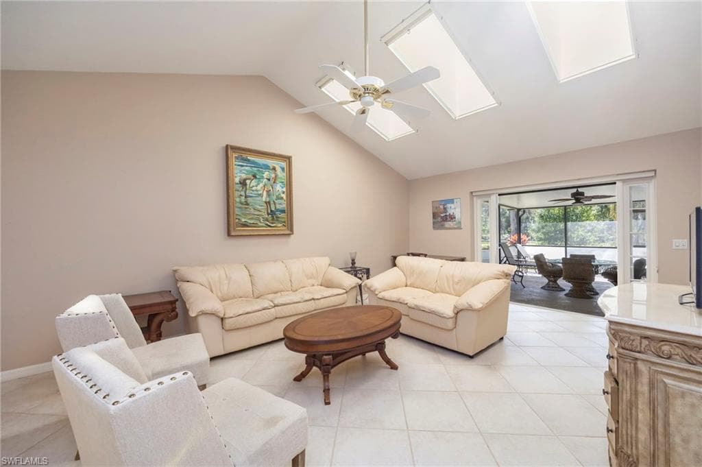Living area with ceiling fan, lofted ceiling, a skylight, and light tile patterned floors