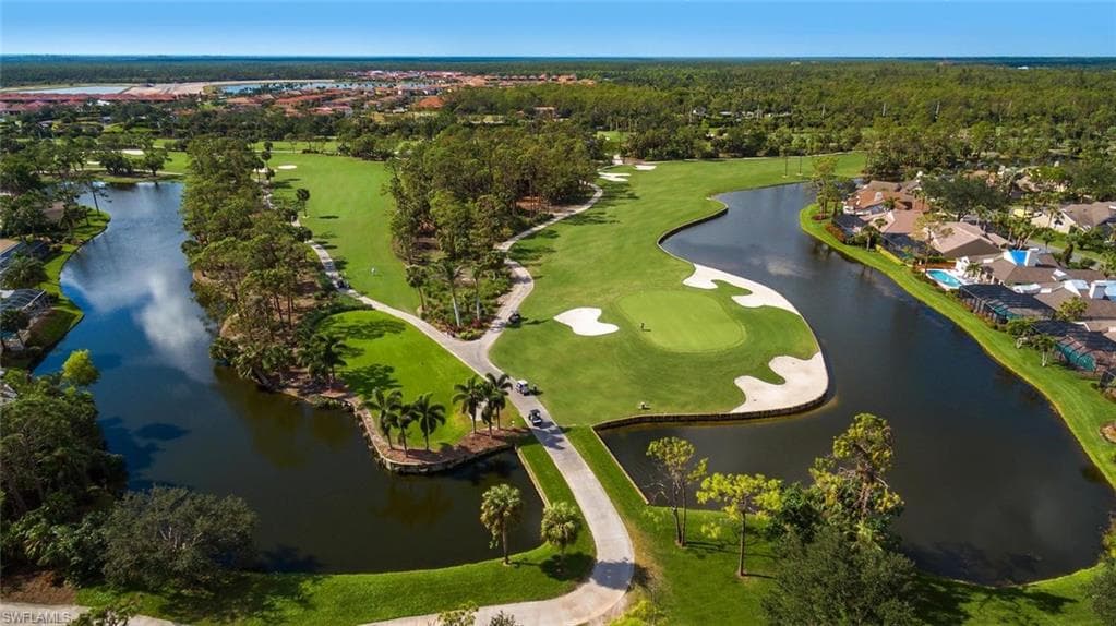 Aerial view of residential area featuring a golf course and a nearby body of water