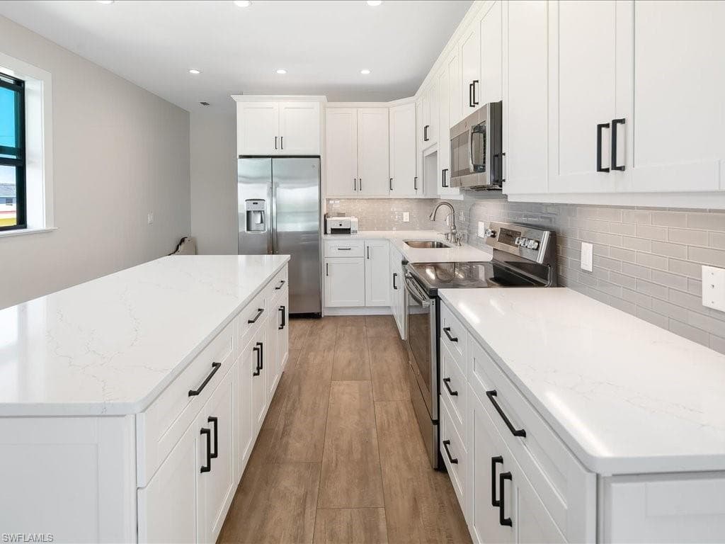 Kitchen featuring stainless steel appliances, a kitchen island, white cabinetry, tasteful backsplash, and recessed lighting