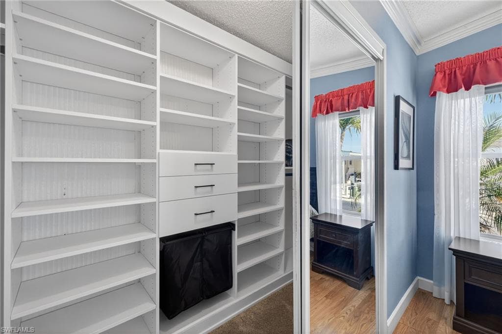 Primary closet with light wood-style flooring