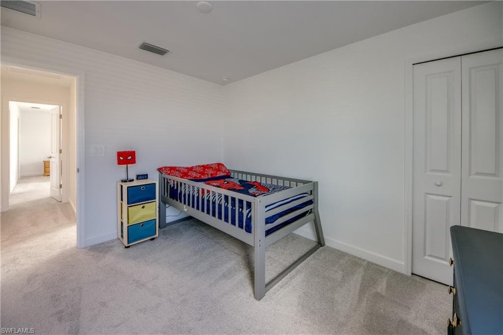 Bedroom with light carpet and a closet