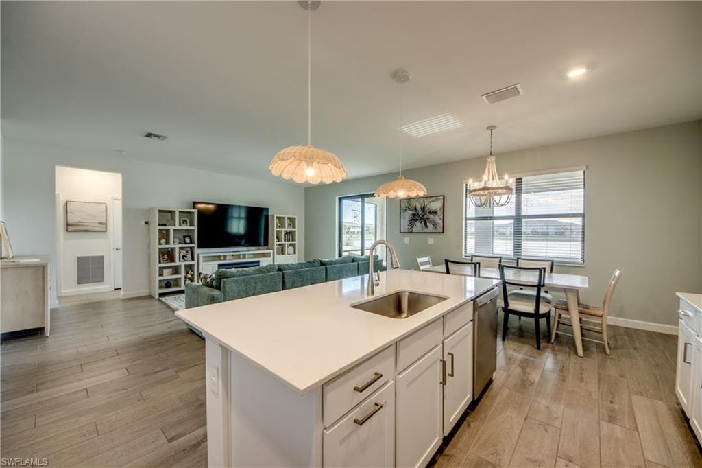 Kitchen with white cabinetry, light wood-type flooring, pendant lighting, a chandelier, and open floor plan