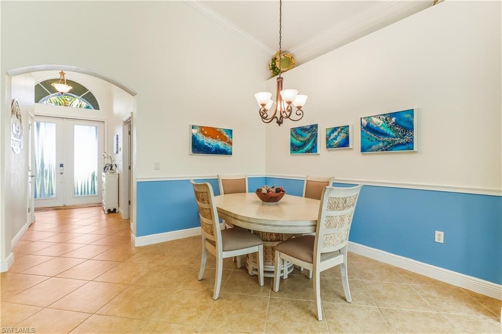 Dining room with arched walkways, french doors, a chandelier, high vaulted ceiling, and light tile patterned floors