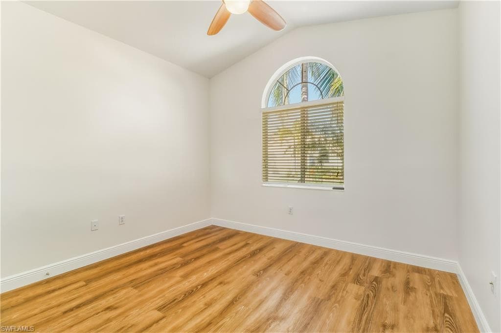 Spare room with vaulted ceiling, wood finished floors, and a ceiling fan