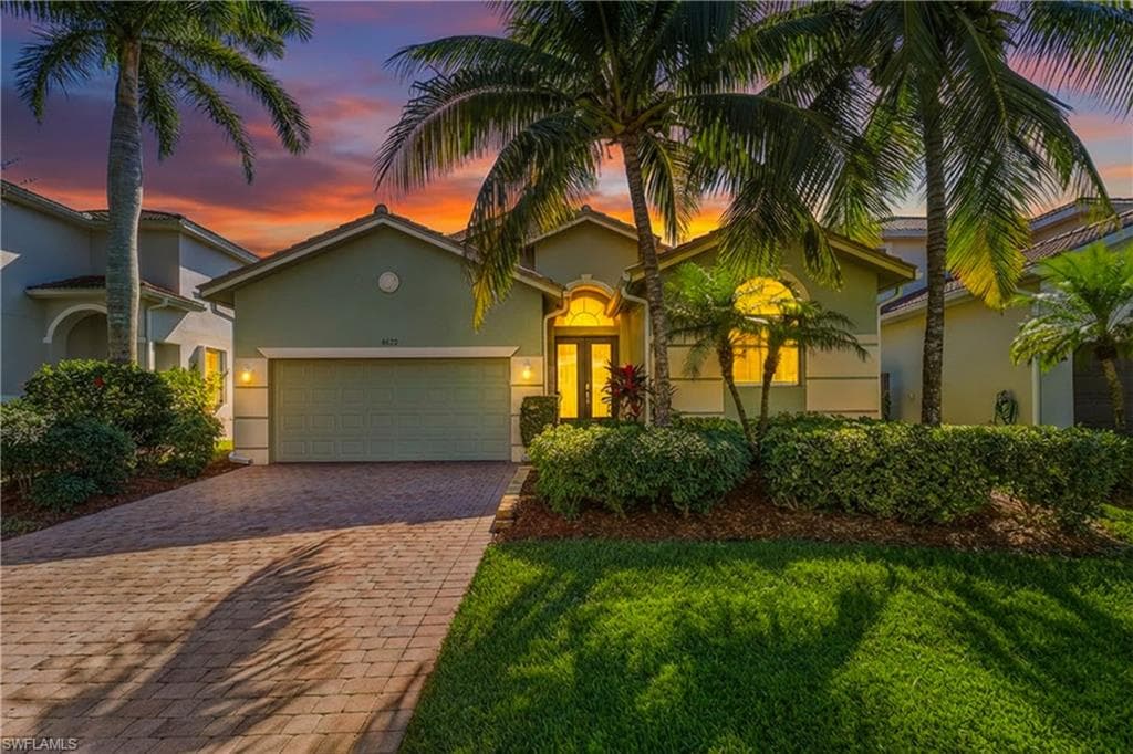 Mediterranean / spanish home featuring an attached garage, a yard, decorative driveway, and stucco siding