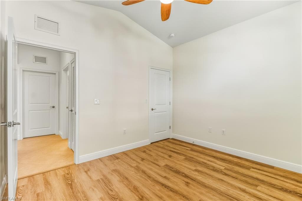Unfurnished bedroom featuring light wood-style flooring, vaulted ceiling, and a ceiling fan