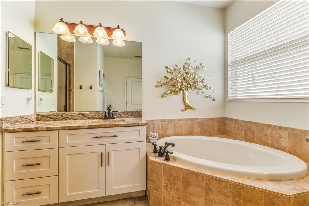 Full bathroom featuring vanity, a garden tub, and a shower stall