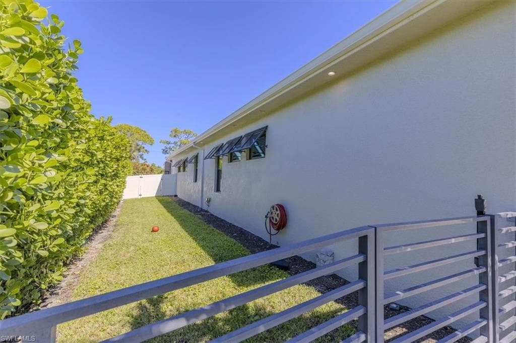 View of side of property with stucco siding and a gate