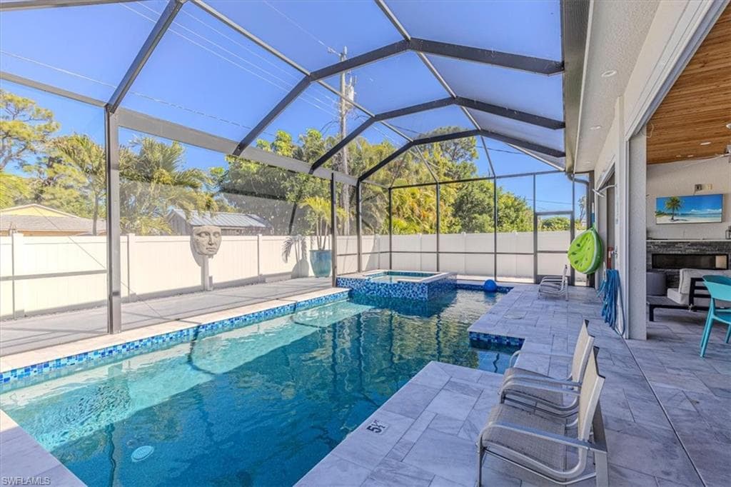 View of pool featuring a sunroom, a patio area, a lanai, and a pool with connected hot tub