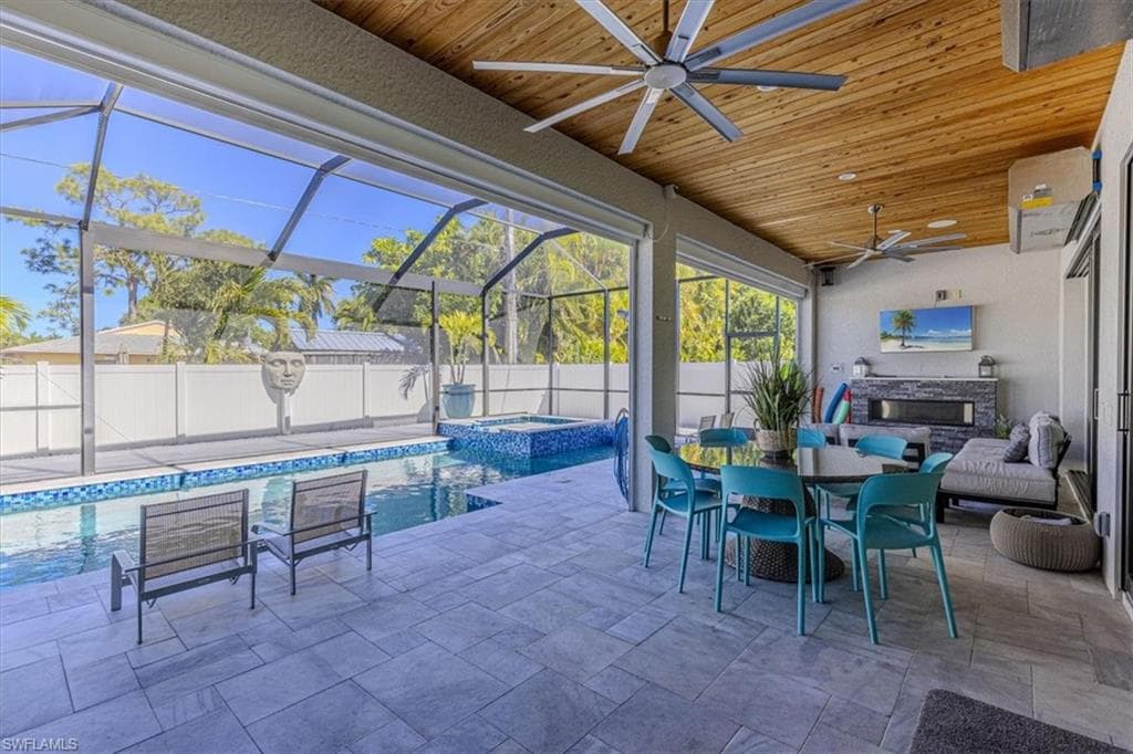 Fenced backyard with outdoor dining area, ceiling fan, a sunroom, glass enclosure, and a patio area