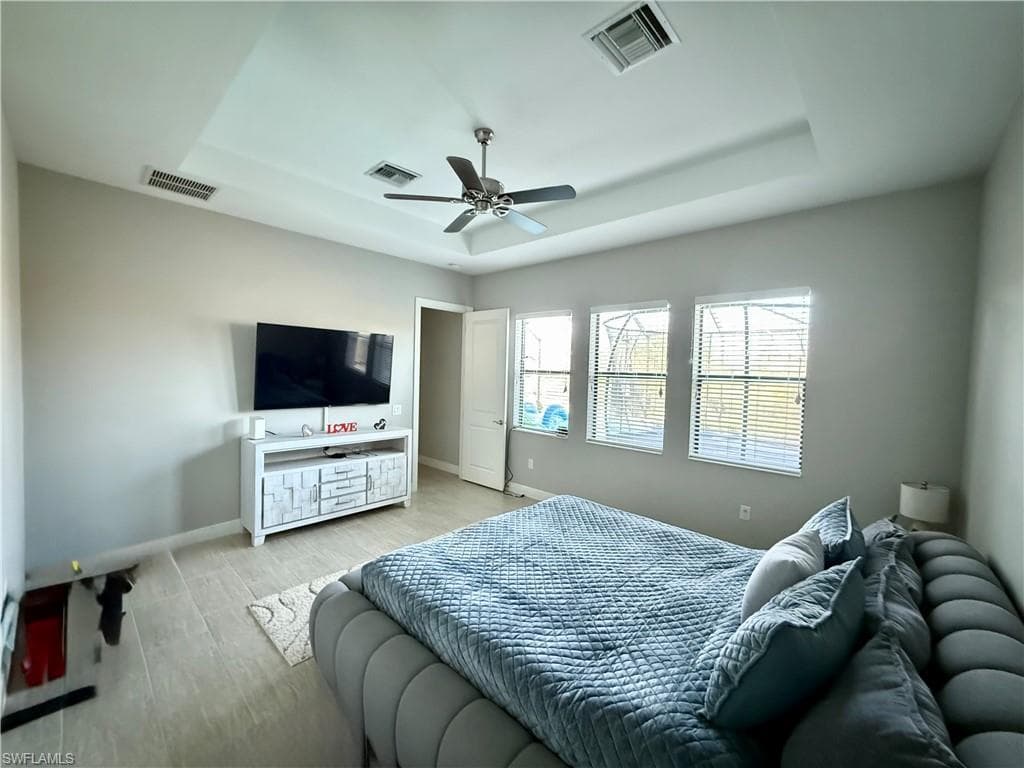 Bedroom featuring a tray ceiling, wood finished floors, and ceiling fan