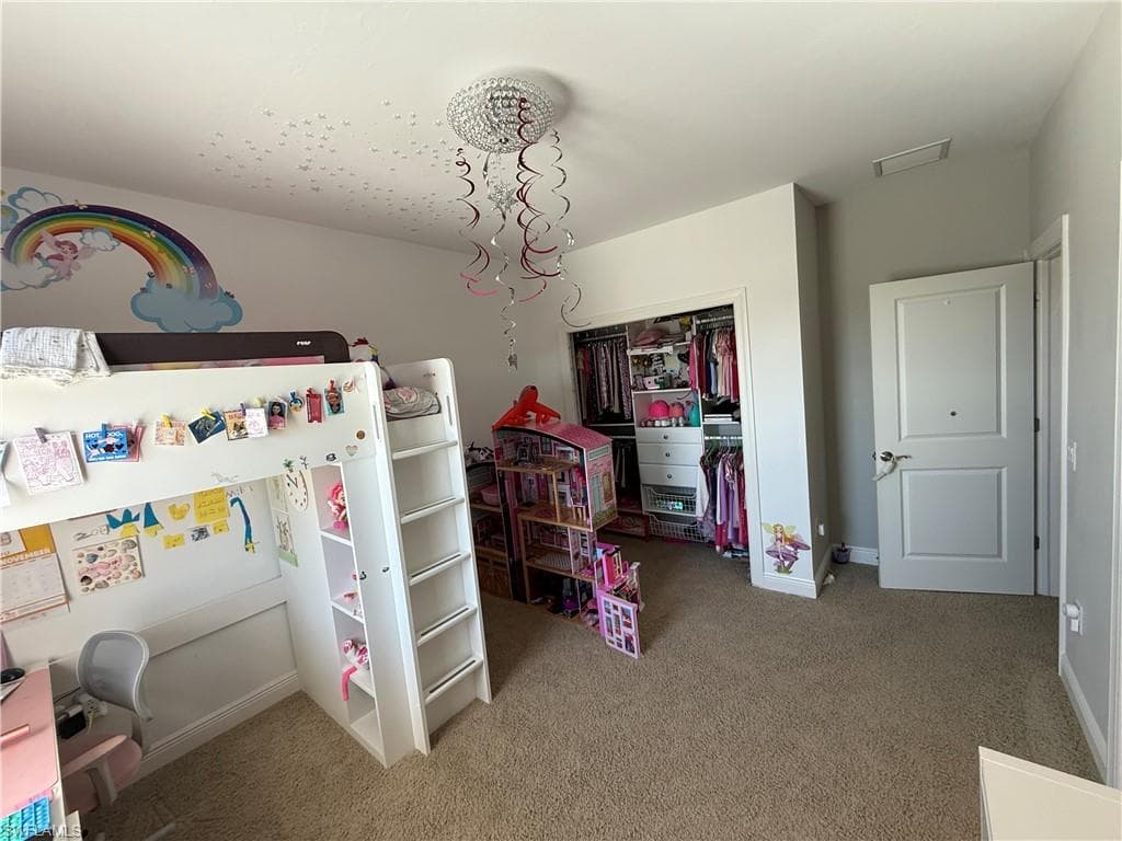 Bedroom with light colored carpet and a chandelier