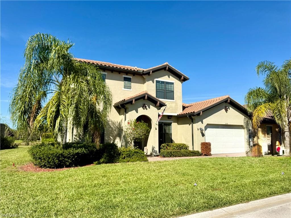 Mediterranean / spanish home featuring a front lawn, a tiled roof, stucco siding, and an attached garage