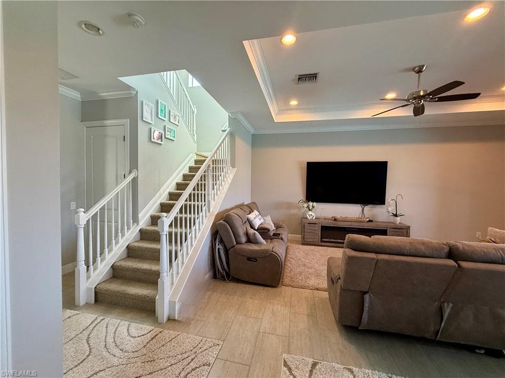 Living area with stairs, ornamental molding, wood finished floors, ceiling fan, and recessed lighting