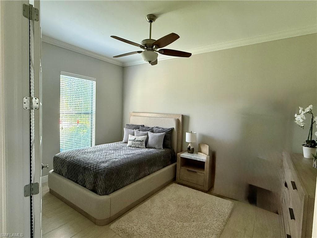 Den used as guest bedroom crown molding, a ceiling fan, and light wood finished floors