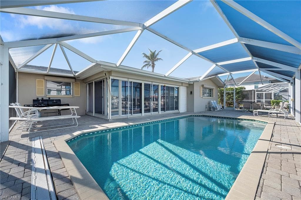 View of pool featuring a sunroom, a patio, and glass enclosure
