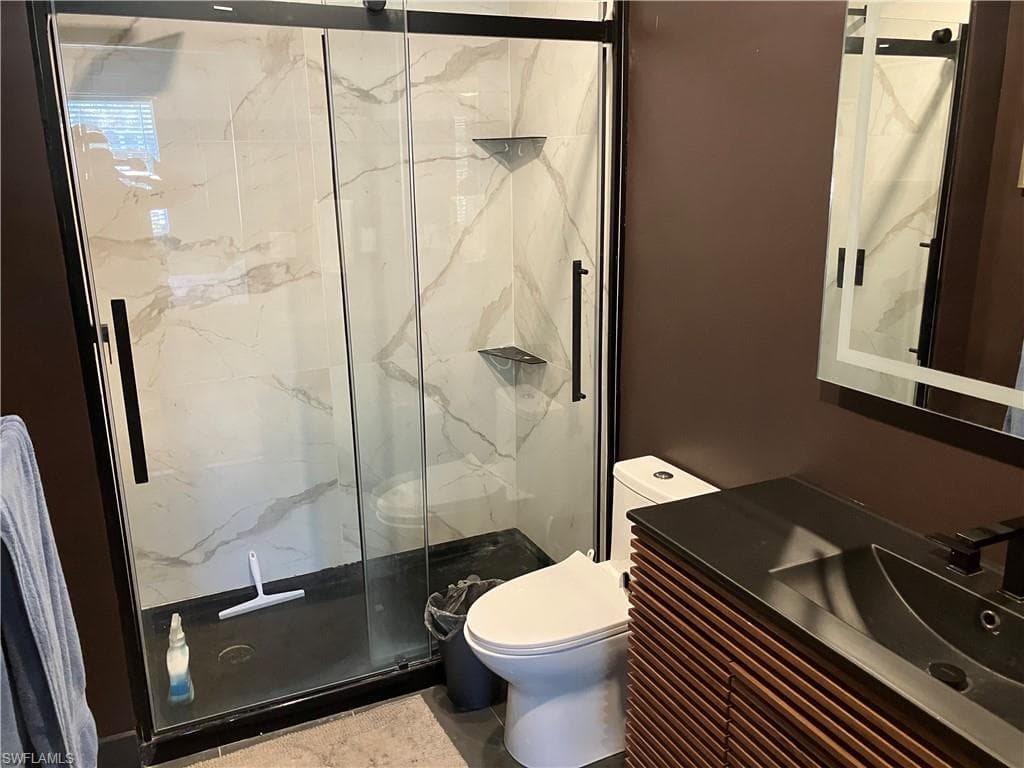 Full bathroom with a marble finish shower and vanity