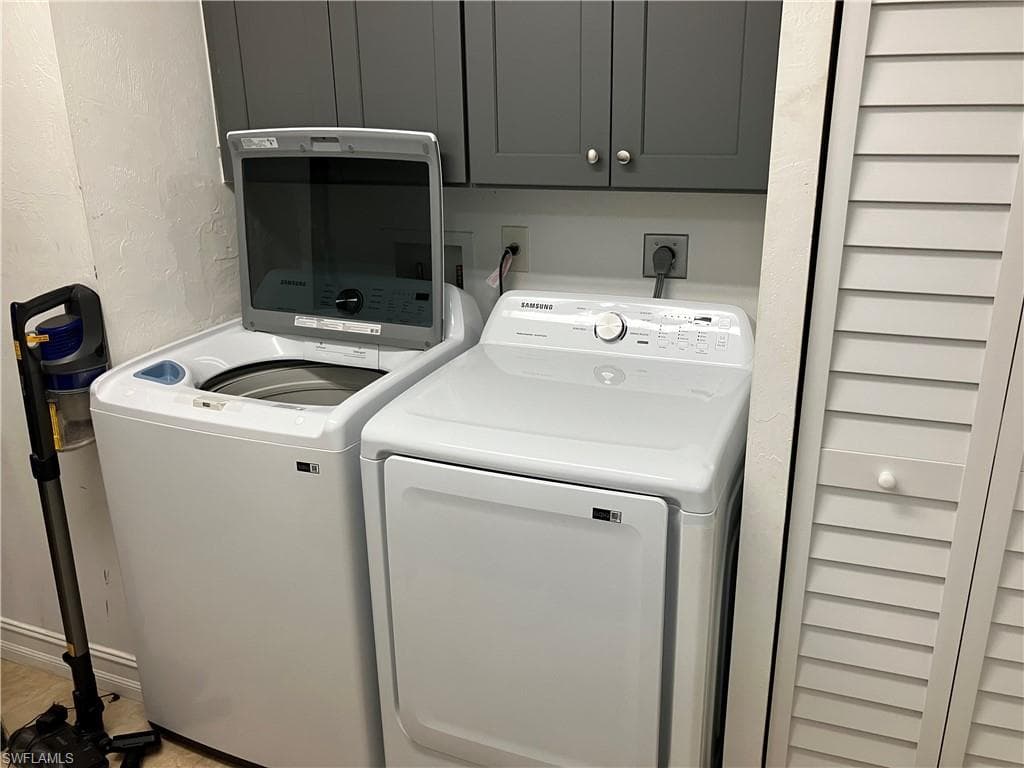 Laundry area featuring a textured wall, washer and dryer, and cabinet space