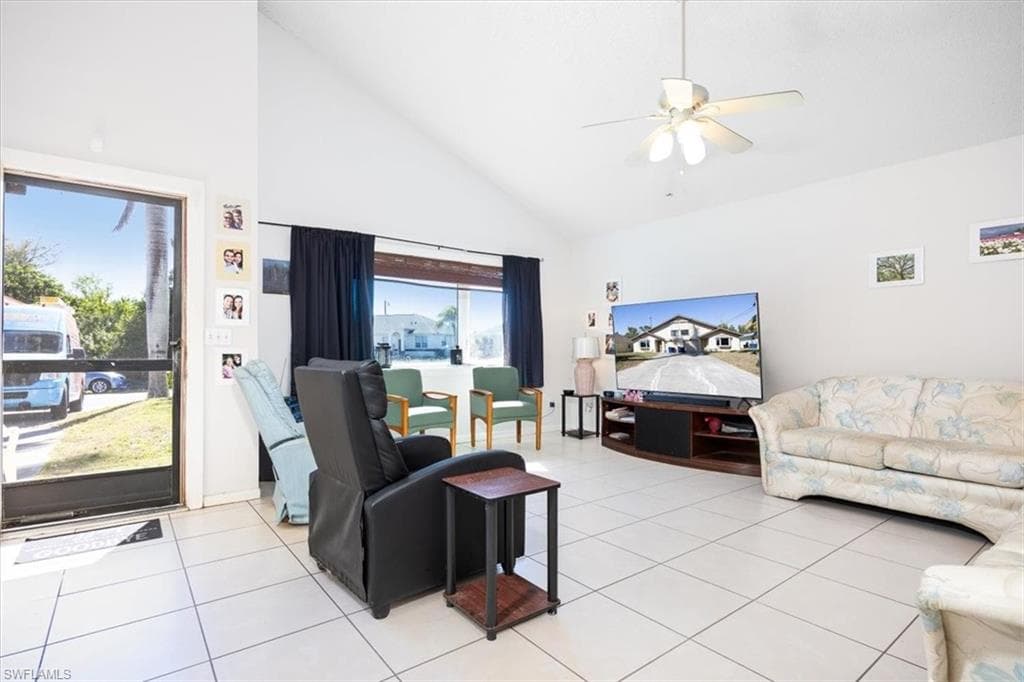 Living area with lofted ceiling, ceiling fan, and light tile patterned floors