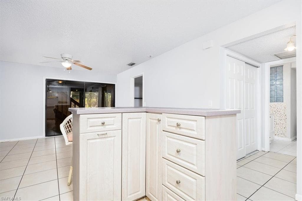 Kitchen with light tile patterned floors, light countertops, ceiling fan, and a textured ceiling