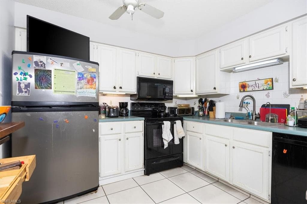 Kitchen with black appliances, white cabinets, ceiling fan, light tile patterned flooring, and backsplash