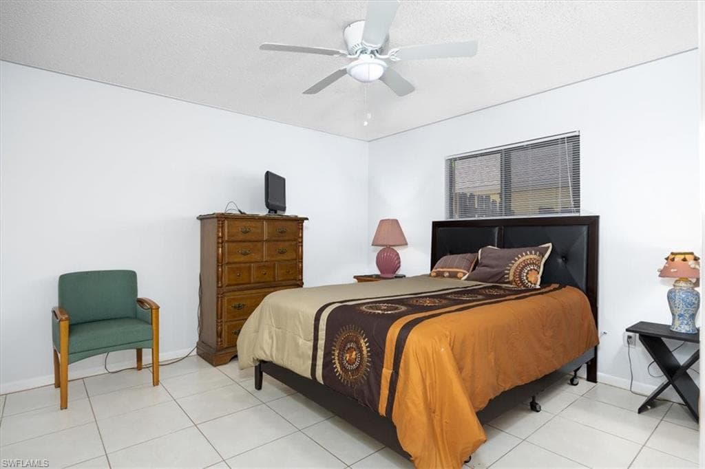 Tiled bedroom with ceiling fan and a textured ceiling