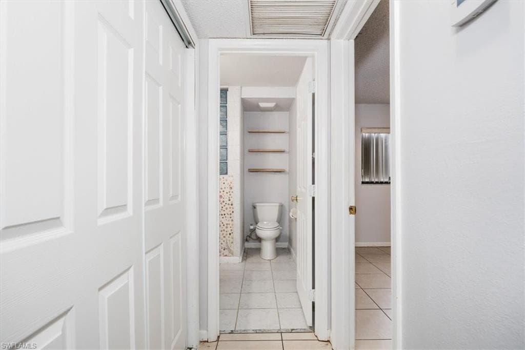 Hall featuring light tile patterned floors and a textured ceiling