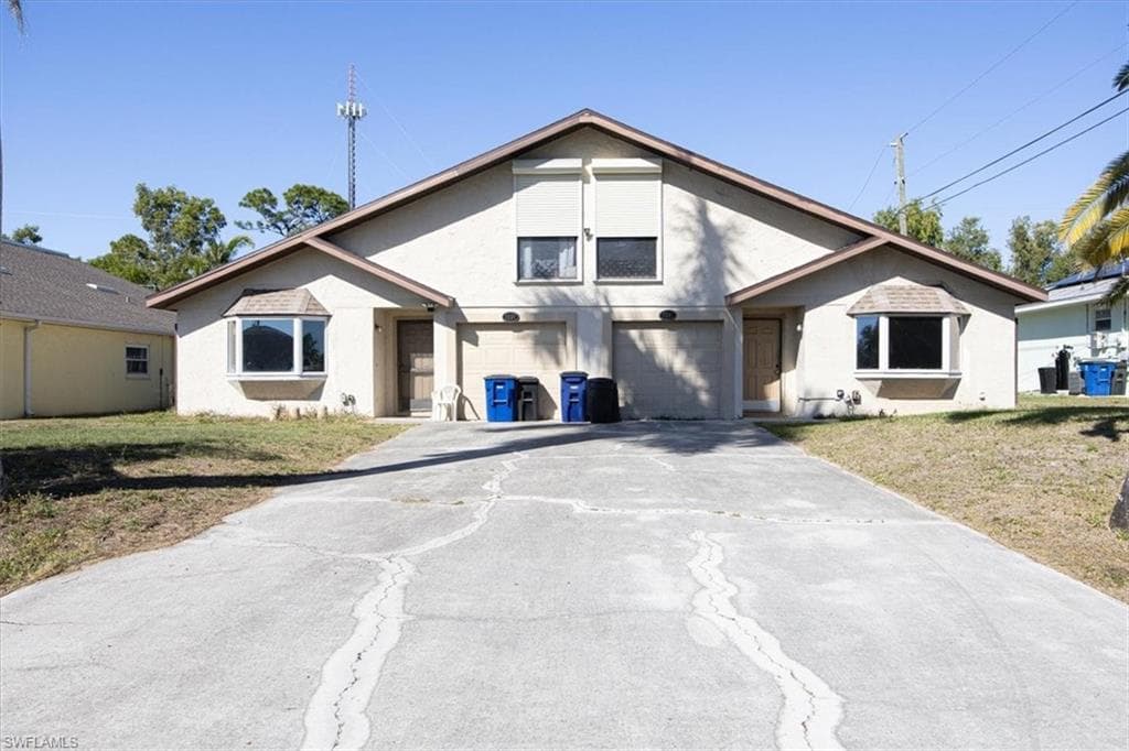 View of front of home with driveway, a front lawn, stucco siding, and a garage