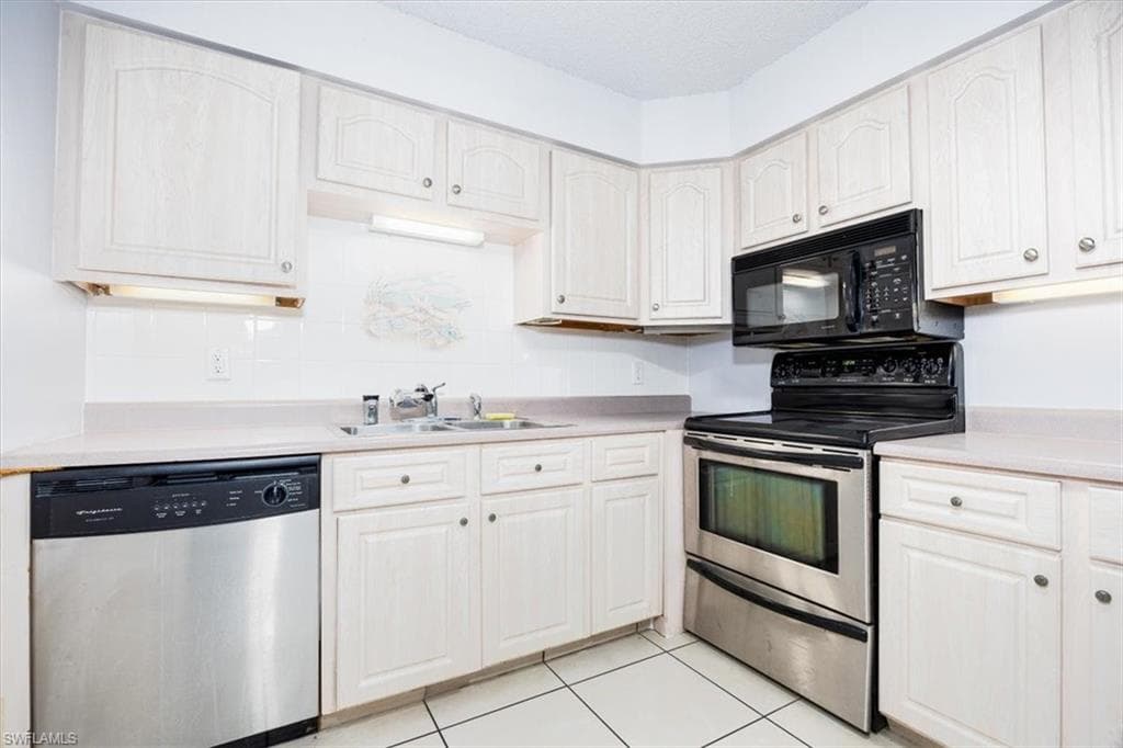 Kitchen with stainless steel appliances, light countertops, and light tile patterned floors