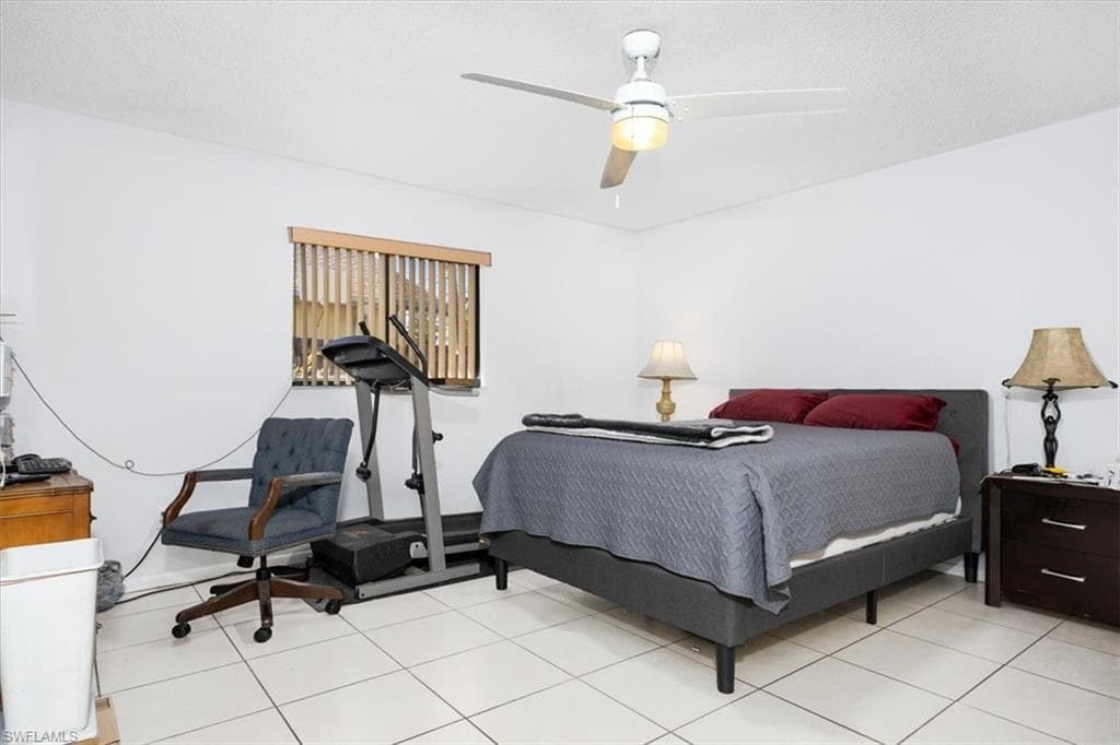 Bedroom with ceiling fan, a textured ceiling, and light tile patterned flooring