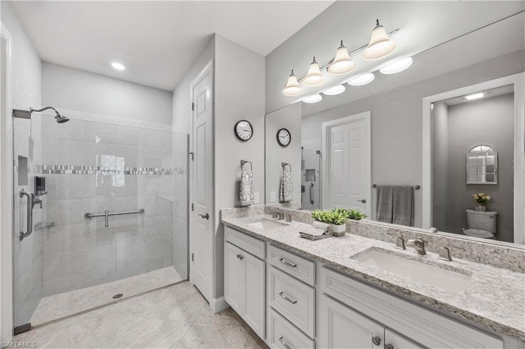Full bath with double vanity and a walk in tile shower, walk in primary closet , linen closet