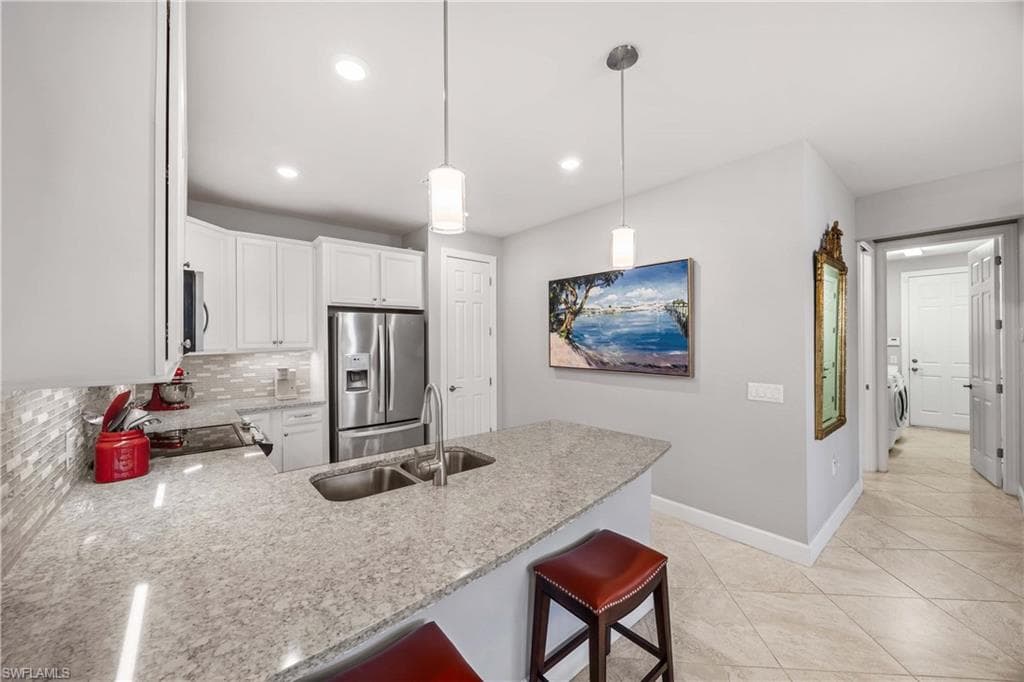 Kitchen with a peninsula, a breakfast bar area, light Quartz countertops, stainless steel appliances, and decorative light fixtures