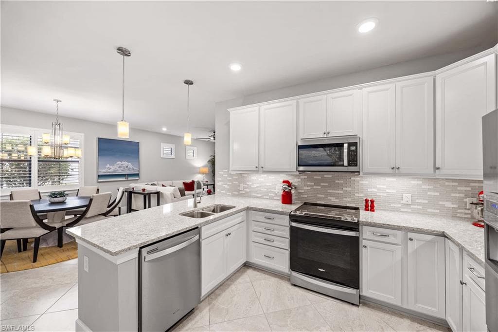 Kitchen with stainless steel appliances, a peninsula, white cabinets, under cabinet lighting, Quartz countertops