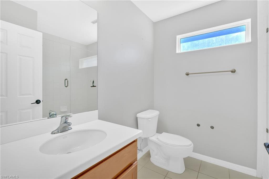 Full bath with vanity, an enclosed shower, and light tile patterned floors