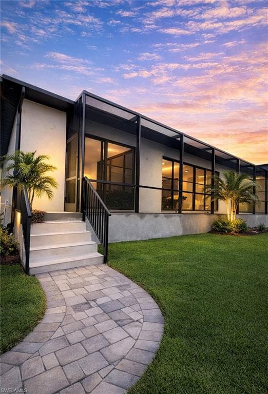 Back of property featuring a lawn, stucco siding, a patio area, and a lanai (Rendered photo)