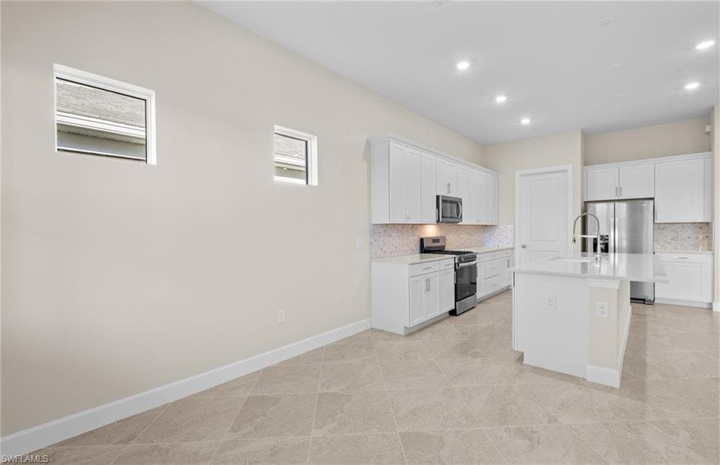 Kitchen with stainless steel appliances, white cabinetry, tasteful backsplash, and recessed lighting