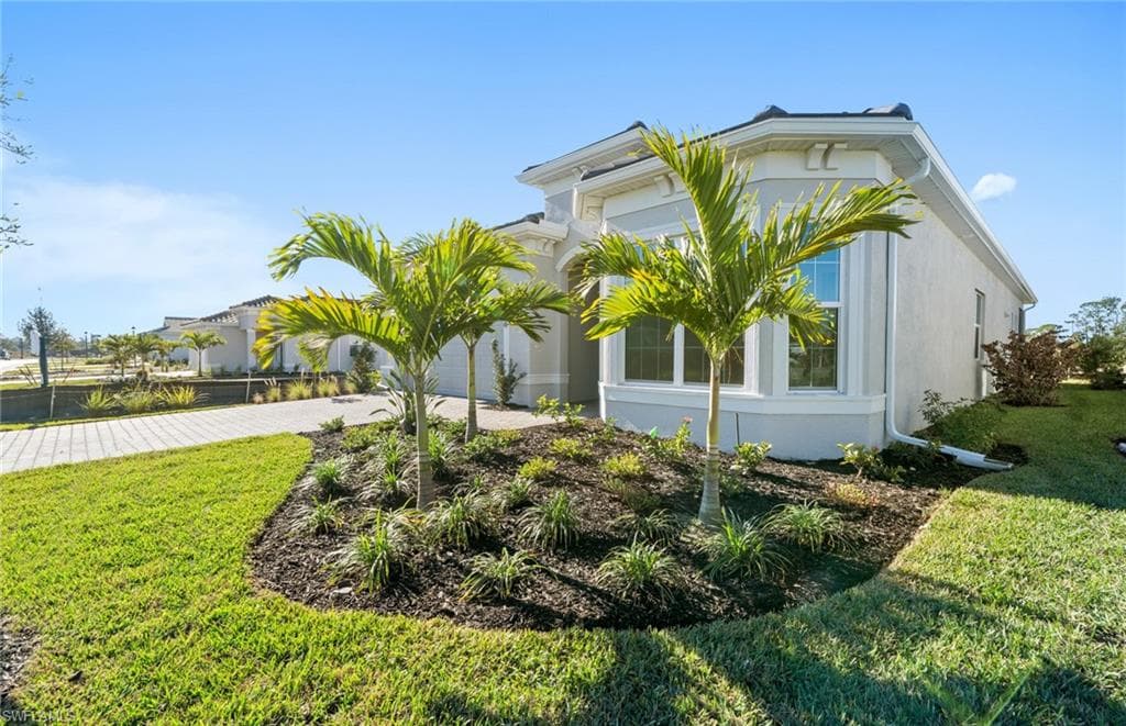 View of front facade featuring driveway, a front lawn, stucco siding, and a garage
