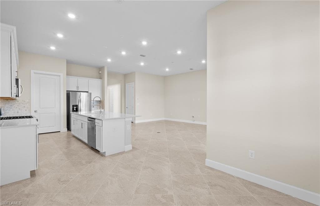 Kitchen featuring white cabinets, recessed lighting, stainless steel appliances, a kitchen island with sink, and open floor plan