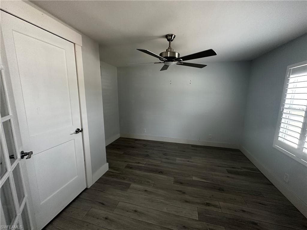 Unfurnished bedroom with dark wood-style floors and ceiling fan