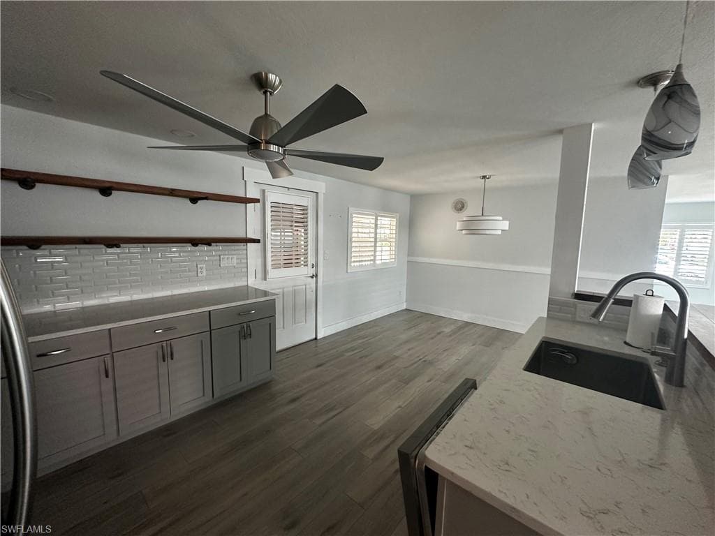 Kitchen featuring pendant lighting, dark wood finished floors, open shelves, fridge, and backsplash