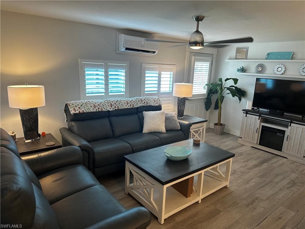 Living area featuring a wall mounted mini split, wood finished floors, and a ceiling fan