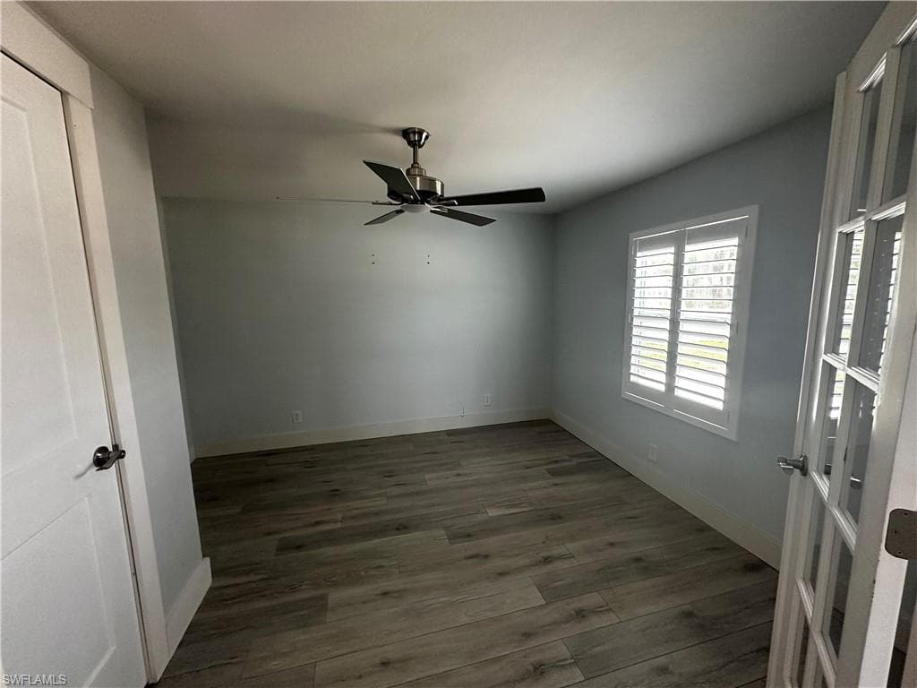 Unfurnished room featuring dark wood-style floors and a ceiling fan