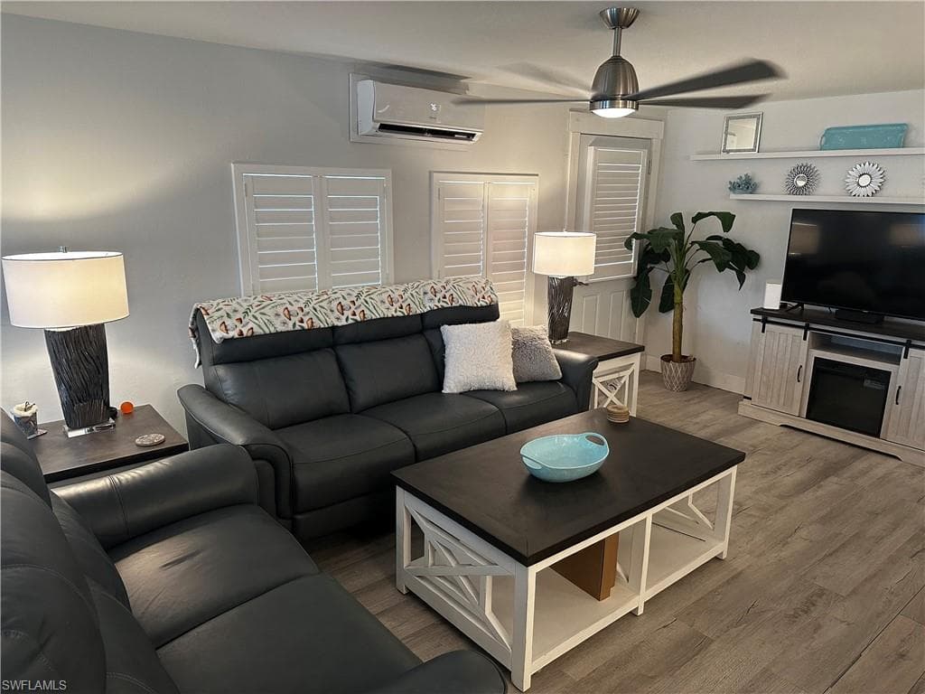 Living room featuring a ceiling fan, a wall mounted mini split, and wood finished floors