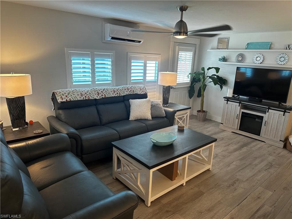 Living room featuring wood finished floors, ceiling fan, and a wall mounted mini split