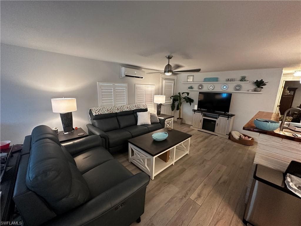 Living area featuring wood-type flooring, a ceiling fan, and a wall mounted mini split