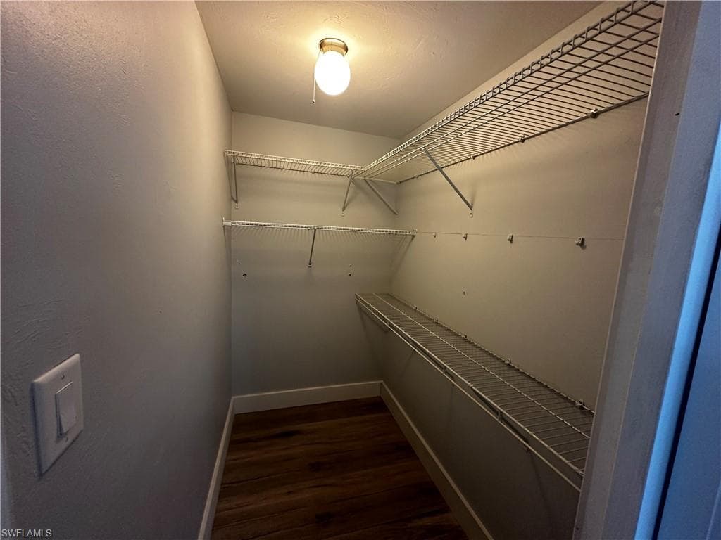 Walk in closet featuring dark wood finished floors